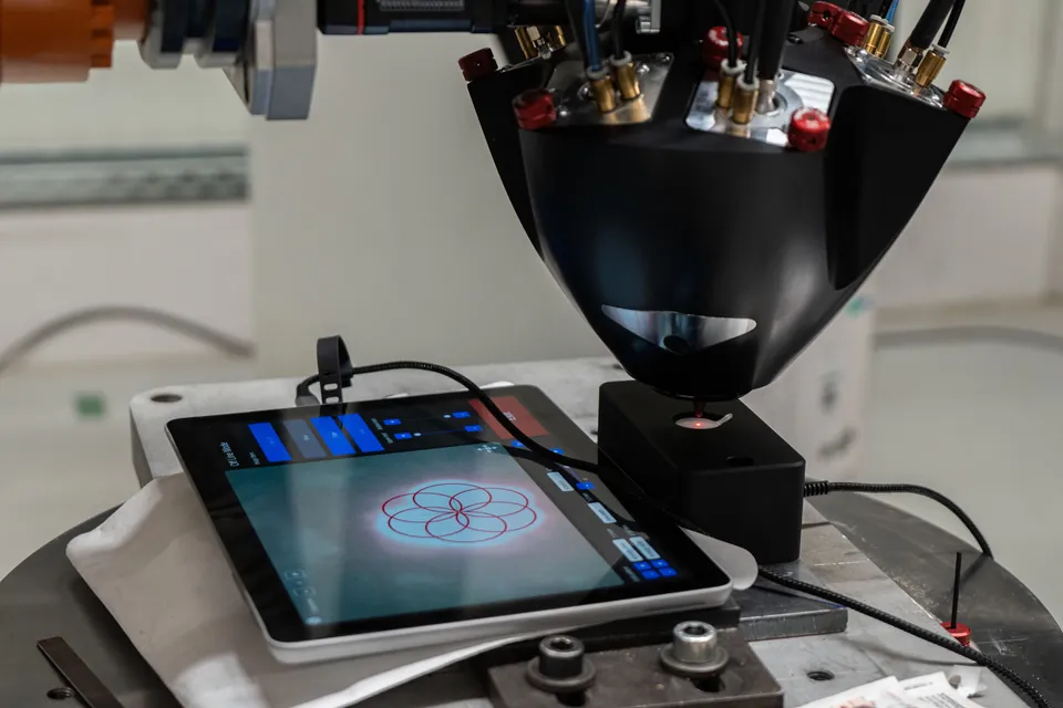 Laser-Draht-Prozesskopf am Roboter über dem Bautisch, daneben das Bedien-Tablet